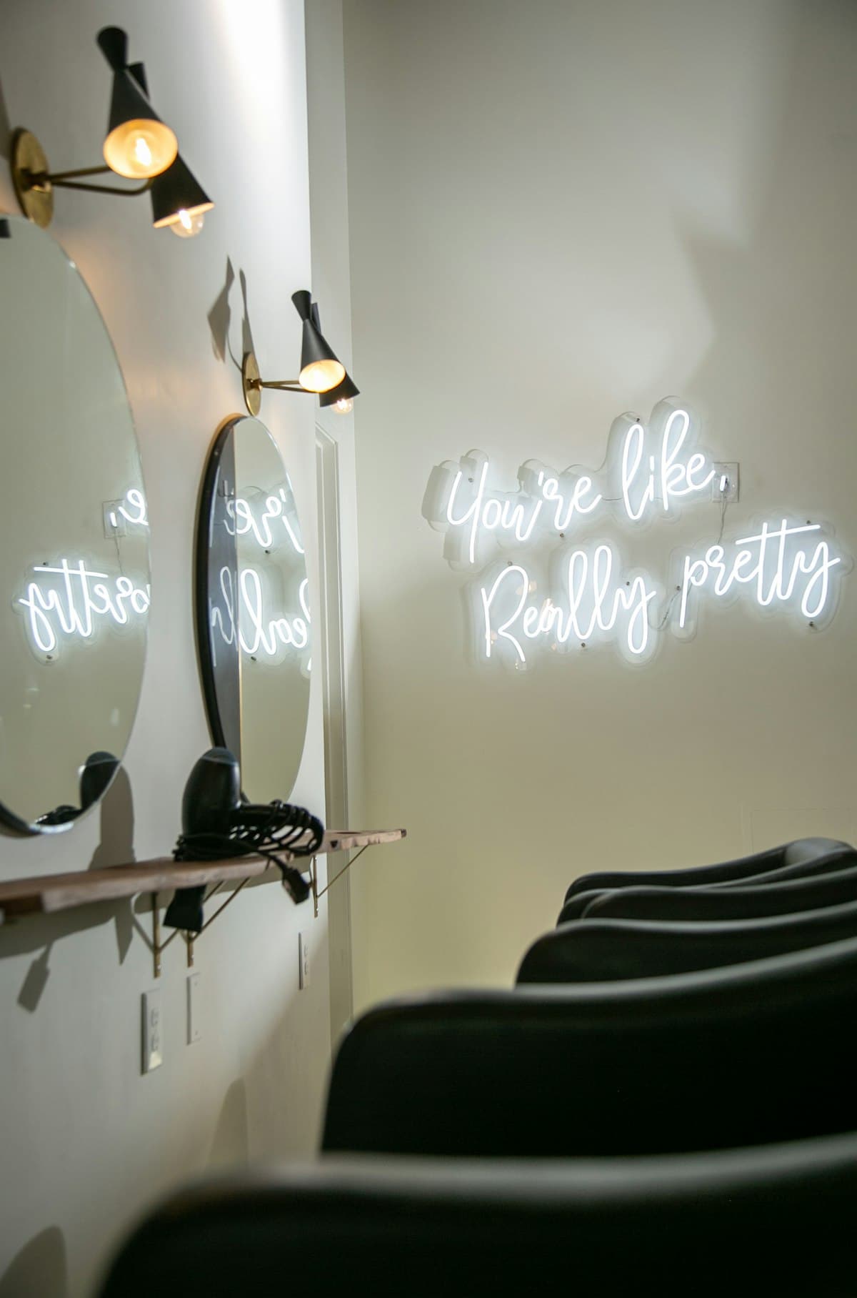 A salon with lit mirrors and a neon sign